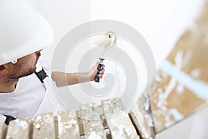 Painter man at work with paint roller, on ladder, wall paintin photo