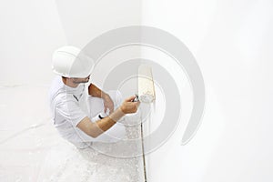 Painter man at work with a paint roller, wall painting