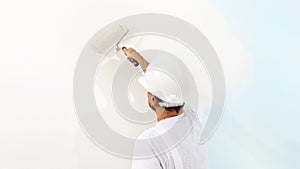 Painter man at work with a paint roller, wall painting