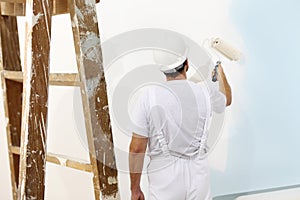 Painter man at work with a paint roller, wall painting