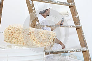 Painter man at work with paint roller, wall painting concept photo