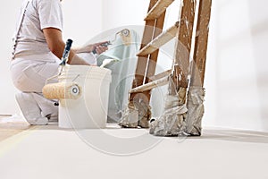 Painter man at work with a roller, bucket and ladder photo