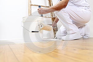 Painter man at work with a roller, bucket and scale, bottom view