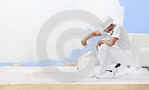 Pintor hombre sobre el tiene una duración pintar rodillo balde vacío blanco muro copiar espacio 