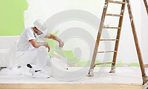 Painter man at work takes the color with roller paint brush from