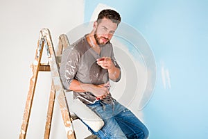 Painter in paint splattered shirt painting a wall