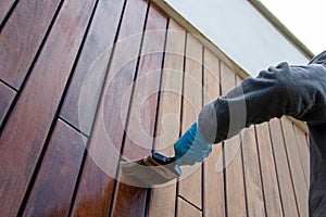 Painter with paintbrush painting house wood facade, dramatic perspective