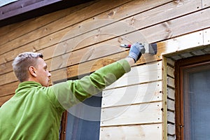 Painter with paintbrush painting house wooden facade