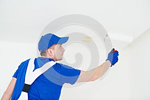 Painter painting ceiling with paint roller