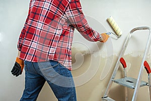 Painter painting a wall with paint roller.