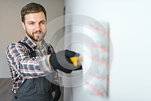 Painter painting a wall with paint roller. Builder worker painting surface with white color