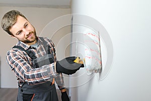 Painter painting a wall with paint roller. Builder worker painting surface with white color