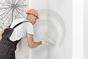 The painter is painting a wall with a roller
