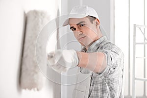 Painter painting a white wall with a roller