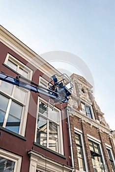 Painter in platform maintaining old building. Deventer, Overijssel, Netherlands.