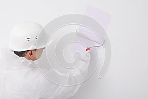 A painter in protective clothing paints a white wall purple