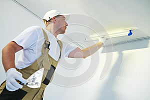 Painter with putty knife. Plasterer smoothing ceiling surface at home renewal