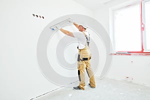 Painter with putty knife. Plasterer smoothing wall surface at home renewal