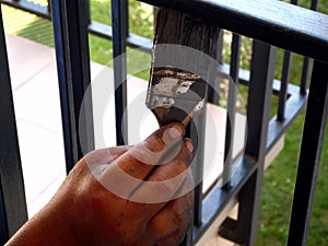 painter`s hand with brush painting steel corridor railing. selective focus.