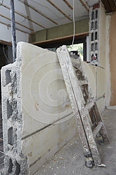 painter\'s ladder stands against a wall in a room of a construction site