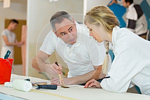 Painter teaching paintbrush technique to apprentice