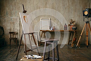 Painter tools and easel in art studio, nobody