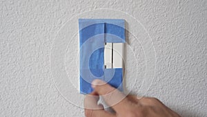 Painter Using Masking Blue Tape to Secure Electric Outlet. Preparation For Room Painting