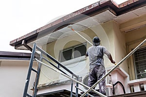 Painter worker adding undercoat foundation paint onto ceiling with roller at residential building photo