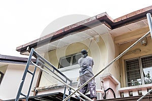 Painter worker adding undercoat foundation paint onto ceiling with roller at residential building photo