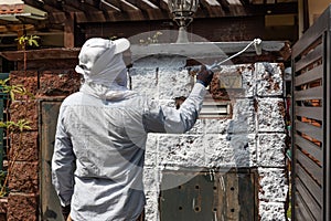 Painter worker adding undercoat foundation paint onto wall with roller at residential building in renovation