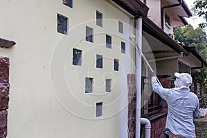 Painter worker adding undercoat foundation paint onto wall with roller at residential building in renovation