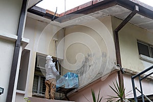Painter worker adding undercoat foundation paint onto wall with roller at residential building in renovation photo
