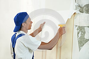 Painter worker peeling off wallpaper photo