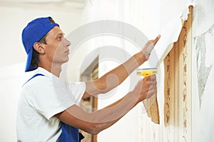 Painter worker peeling off wallpaper