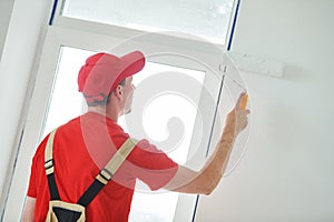 Painter worker with roller painting wall surface into white