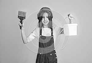 painter in workshop. renovation and repair. teen girl in helmet and boilersuit with painting brush and bucket. child