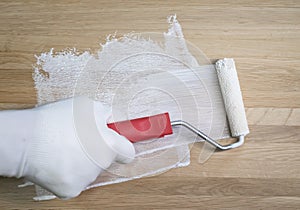 Painting and coloring with white colour wooden surface with paint roller, close up