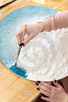 painting and drawing. girl paints on a round canvas, blue paint