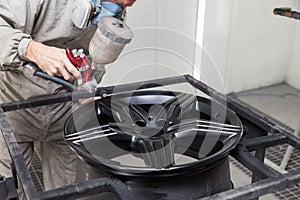 Painting the element body of the car - the aluminum alloy wheel with the help of aerograf in black color by the hand of painter photo