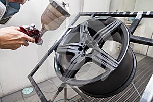 Painting the element body of the car - the aluminum alloy wheel with the help of aerograf in black color by the hand of painter