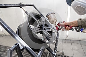 Painting the element body of the car - the aluminum alloy wheel with the help of aerograf in black color by the hand of painter photo