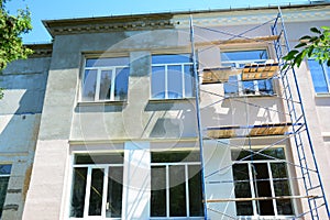 Painting house facade wall outdoors. Painting plastering exterior walls with light pink paint