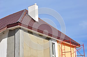 Painting house walls. House renovation with metal roof repair, house insulation, soffits and painting walls