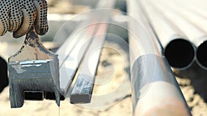 Painting of metal structures with anticorrosive paint. The worker's hand paints the metal with a brush.