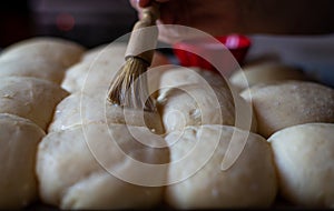 Painting milk on uncooked Bread rolls. ,making bread rolls at home. hobby