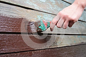 Painting old wooden wall surface with paint brush