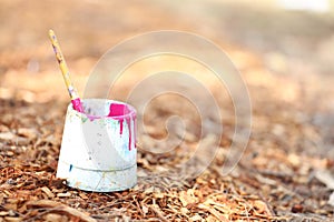 painting outdoors. pink paint in a bucket on bark