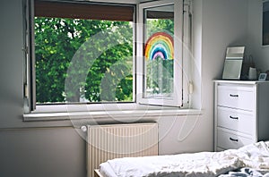 Painting rainbow on open window in room. Spring time