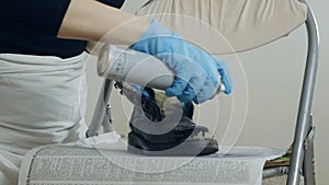 Painting and restoration of shoes at home. Close-up of a woman's hands in gloves, takes care of her shoes, sprays