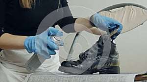 Painting and restoration of shoes at home. Close-up of a woman's hands in gloves, takes care of her shoes, sprays